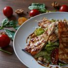 Delicious grilled chicken salad served with fresh tomatoes and walnuts on the side.